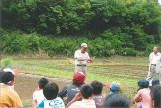 子ども達に米作りの説明をする小嶋さん。