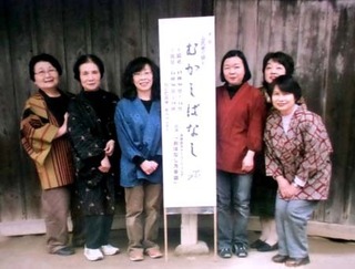 おはなし会の立て札の脇に並ぶ6人の女性会員の写真