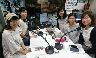 狭いラジオブースの中で笑顔の浮かべる5人の女性の写真